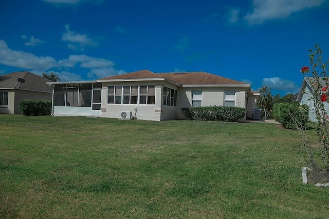 back of property featuring a yard, central air condition unit, a sunroom, and stucco siding