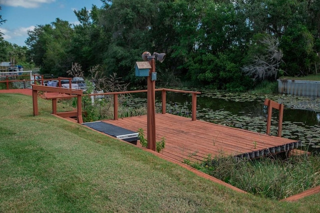 wooden deck featuring a water view and a lawn