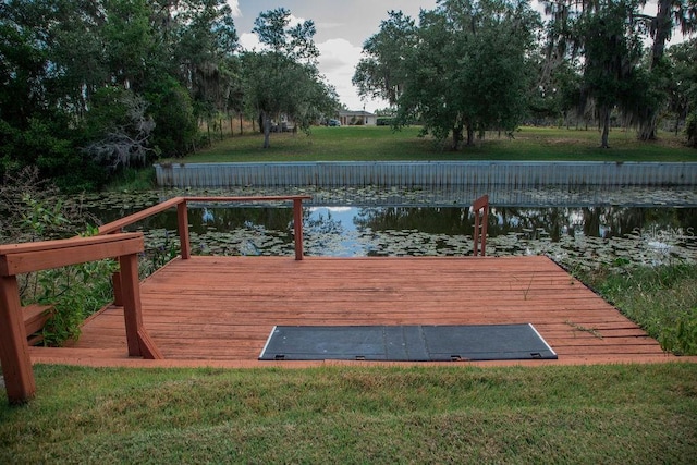 dock area with a lawn and a water view