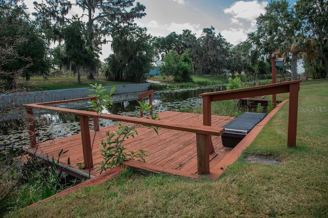 wooden deck featuring a water view, a boat dock, and a lawn