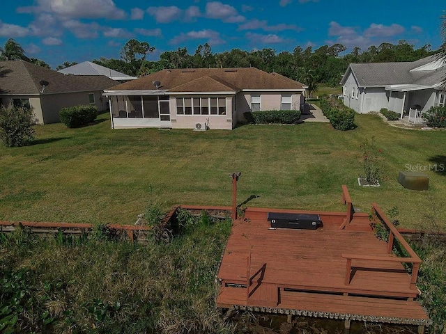 back of house with a wooden deck, a sunroom, and a lawn