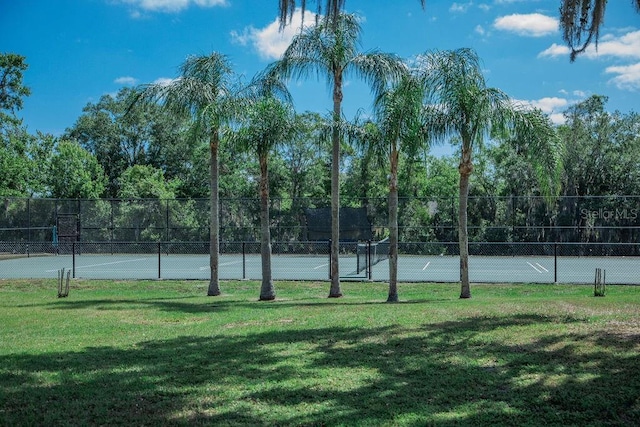 view of sport court featuring fence and a lawn