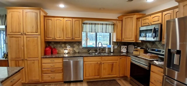 kitchen featuring a sink, dark stone countertops, tasteful backsplash, recessed lighting, and appliances with stainless steel finishes