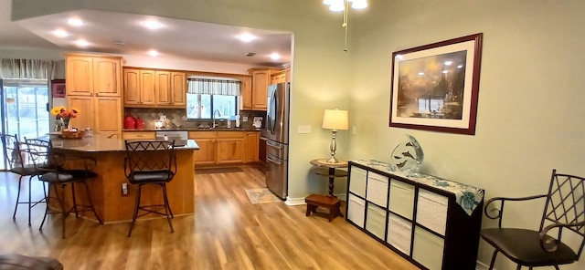 kitchen featuring a breakfast bar area, a center island, light wood-style floors, decorative backsplash, and appliances with stainless steel finishes