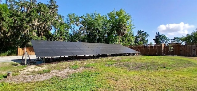 view of outbuilding featuring solar panels and fence
