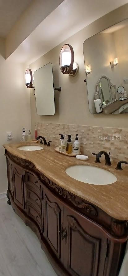 bathroom with double vanity, decorative backsplash, and a sink