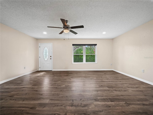 interior space with a ceiling fan, a textured ceiling, dark wood-style floors, and baseboards