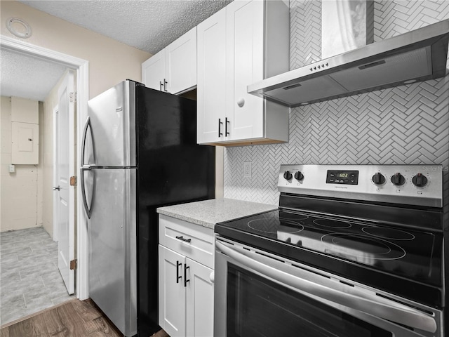 kitchen with wall chimney range hood, light countertops, white cabinets, tasteful backsplash, and stainless steel appliances