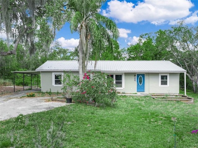 ranch-style home with a carport, metal roof, a front lawn, and stucco siding