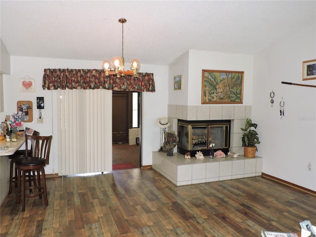 living area with wood-type flooring, baseboards, an inviting chandelier, and a tiled fireplace