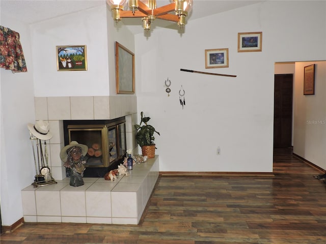 living room with a tiled fireplace, lofted ceiling, wood finished floors, and an inviting chandelier