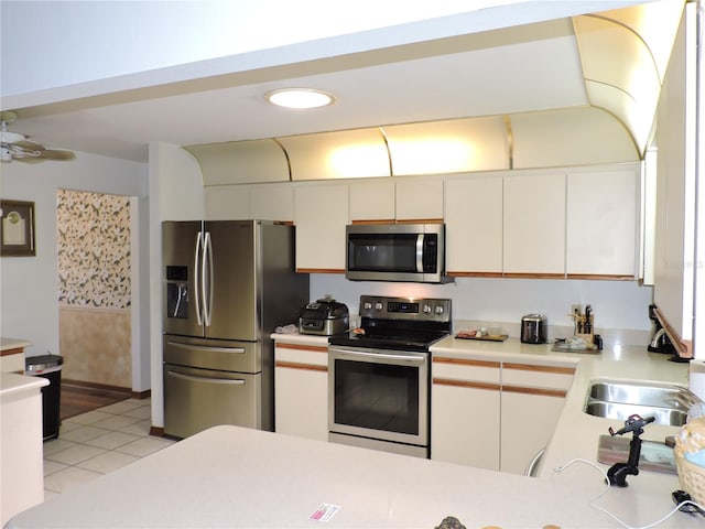 kitchen featuring light countertops, a sink, appliances with stainless steel finishes, and light tile patterned flooring