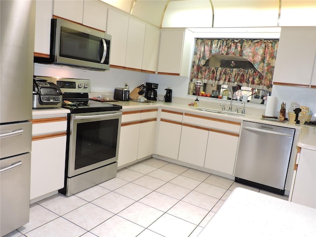 kitchen with light countertops, a sink, light tile patterned floors, and stainless steel appliances