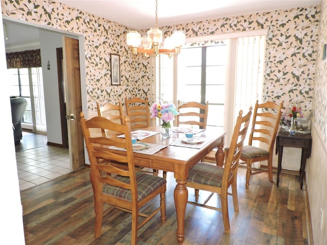 dining area with an inviting chandelier, wallpapered walls, and wood finished floors