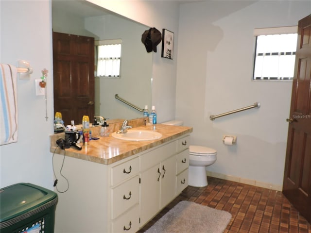 bathroom with vanity, brick patterned floor, and toilet