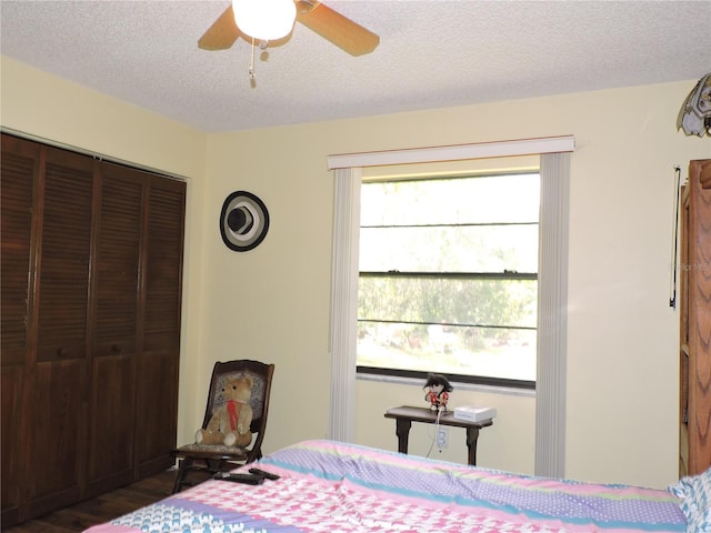 bedroom with a ceiling fan, a textured ceiling, wood finished floors, and a closet