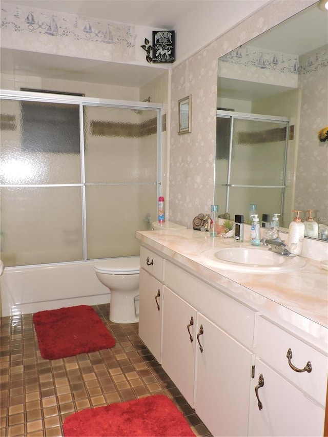 bathroom featuring tile patterned flooring, vanity, bath / shower combo with glass door, toilet, and wallpapered walls