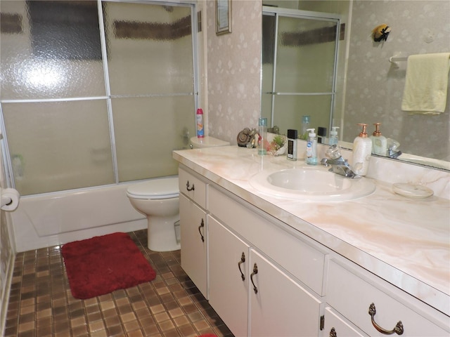 bathroom featuring toilet, wallpapered walls, combined bath / shower with glass door, and vanity
