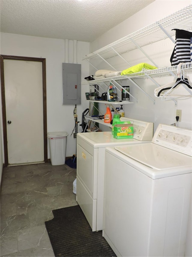 laundry room with laundry area, washing machine and dryer, a textured ceiling, and electric panel