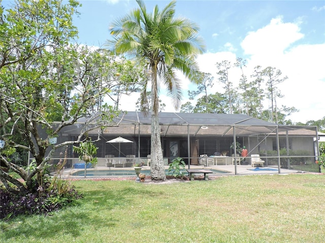 rear view of property with a patio, a yard, and an outdoor pool