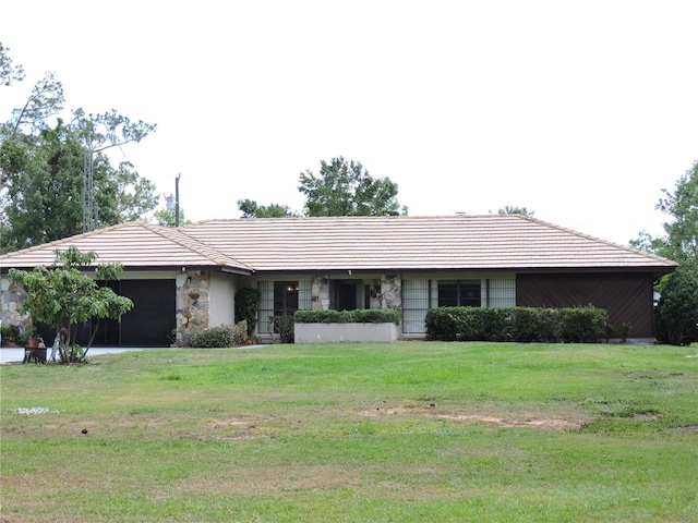 single story home featuring a garage, a front yard, and stone siding