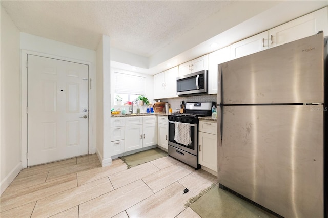 821 Orchid Springs Dr Unit 821, Winter Haven, FL 33884 - kitchen with stainless steel appliances, white cabinets, a sink, a textured ceiling, and wood finish floors