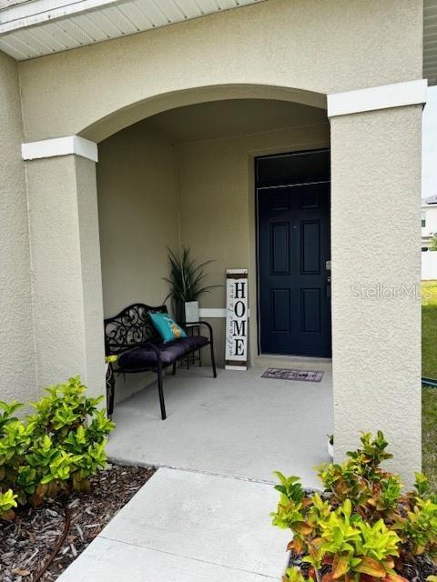 view of exterior entry featuring stucco siding and covered porch