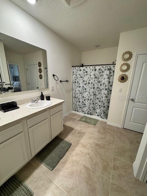 full bath with vanity, tile patterned flooring, a shower with shower curtain, a textured ceiling, and baseboards