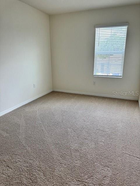 unfurnished room with carpet and baseboards