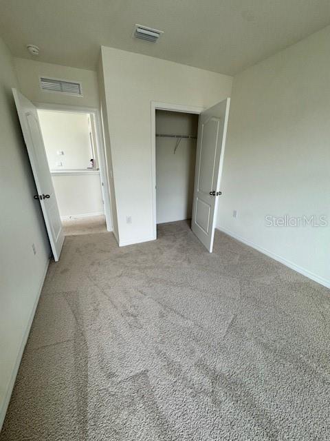 unfurnished bedroom with light colored carpet, baseboards, and a closet