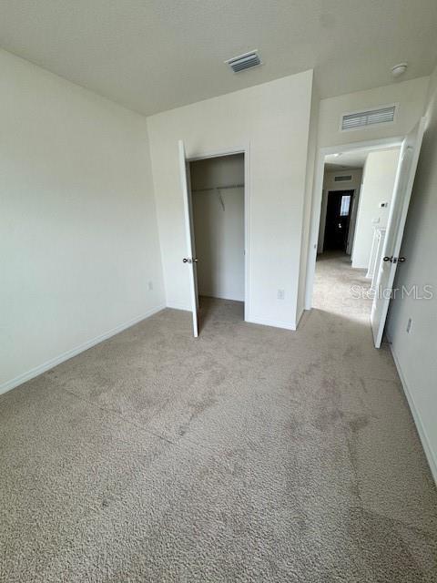 unfurnished bedroom featuring light colored carpet, baseboards, and a closet