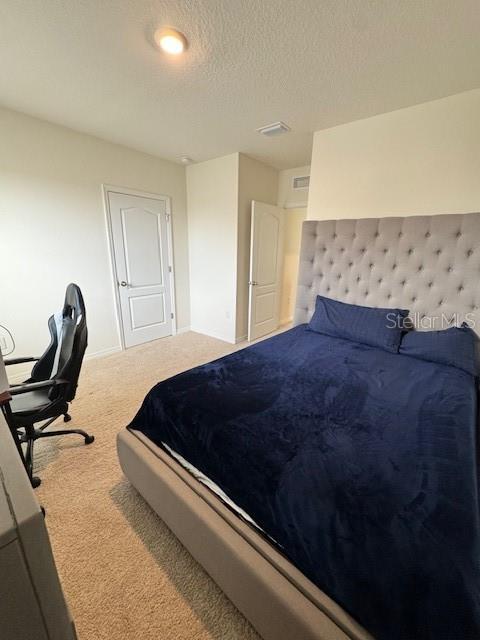 bedroom featuring carpet floors, baseboards, and a textured ceiling