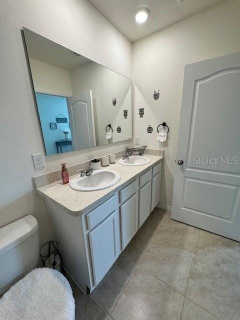 full bath featuring toilet, double vanity, and tile patterned flooring