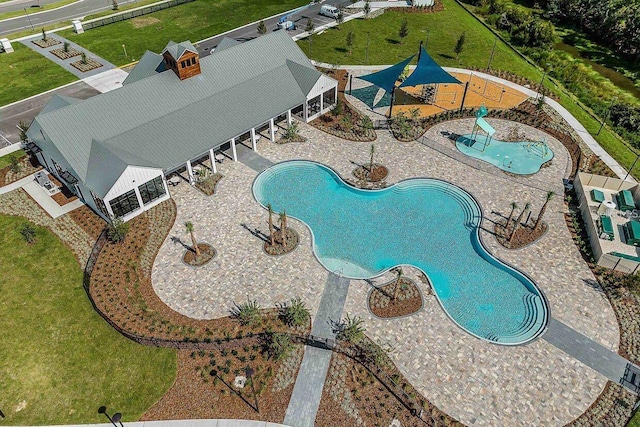 community pool with a water play area, a water slide, and fence