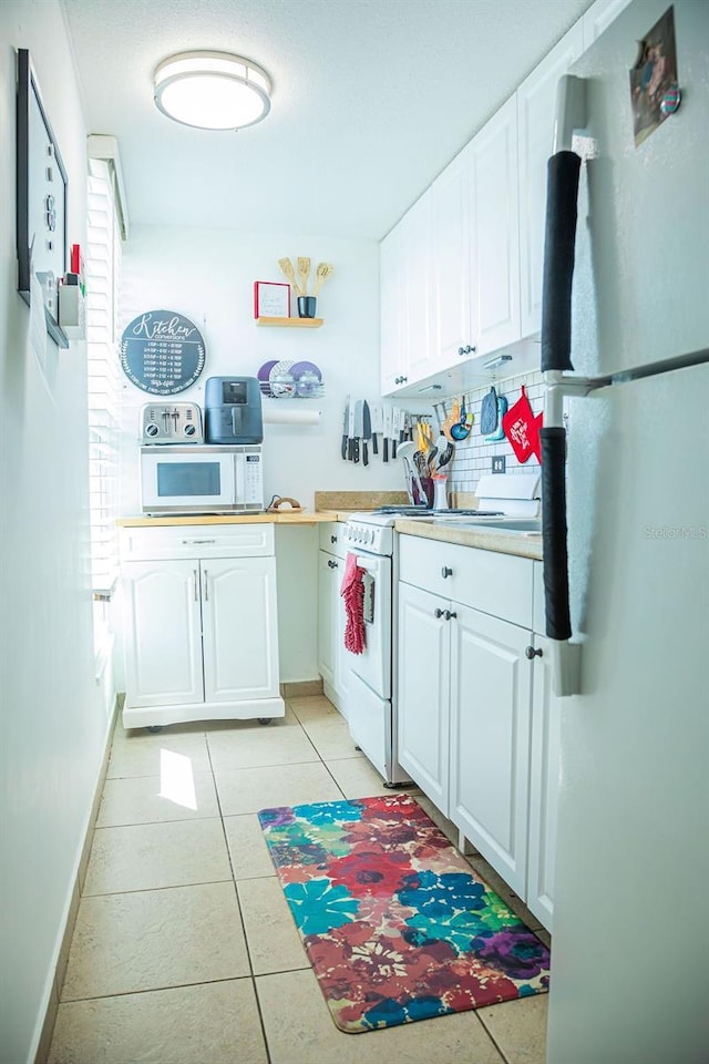 3041 Club Cir, Lake Wales, FL 33898 - kitchen featuring white appliances, white cabinets, light countertops, and light tile patterned flooring