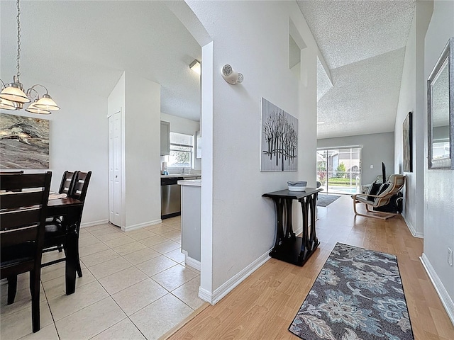 2200 Mallory Cir, Haines City, FL 33844 - hall with a textured ceiling, a chandelier, arched walkways, light wood-type flooring, and baseboards