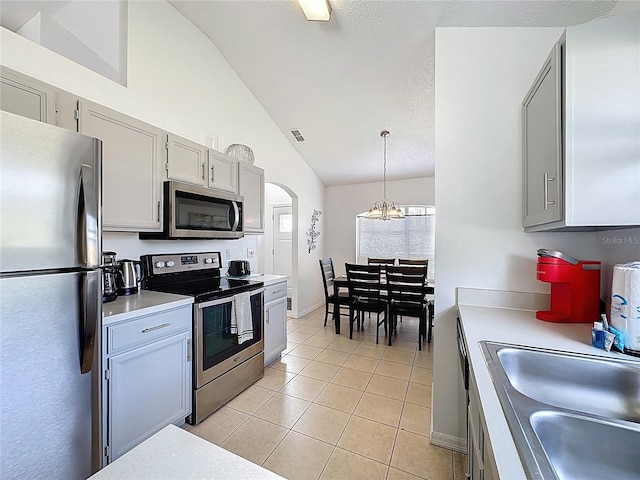 2200 Mallory Cir, Haines City, FL 33844 - kitchen featuring appliances with stainless steel finishes, lofted ceiling, a sink, light tile patterned flooring, and arched walkways