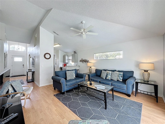 2200 Mallory Cir, Haines City, FL 33844 - living room featuring vaulted ceiling, plenty of natural light, light wood finished floors, ceiling fan, and a textured ceiling
