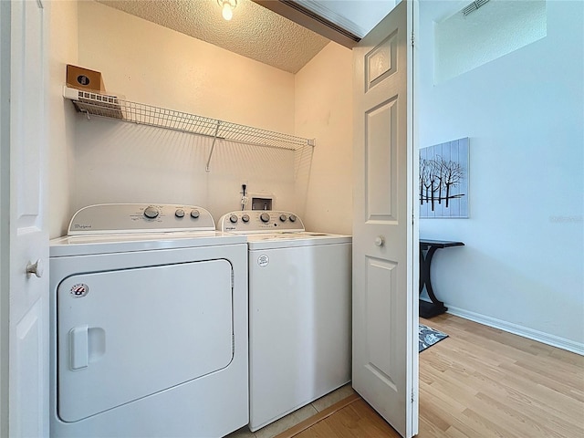 2200 Mallory Cir, Haines City, FL 33844 - clothes washing area with separate washer and dryer, light wood-style floors, a textured ceiling, and baseboards