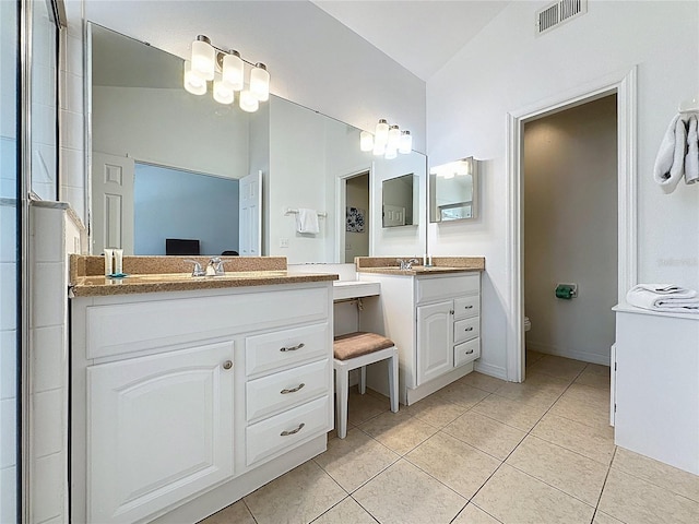 2200 Mallory Cir, Haines City, FL 33844 - bathroom with tile patterned floors, lofted ceiling, toilet, two vanities, and baseboards