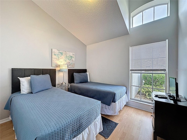 2200 Mallory Cir, Haines City, FL 33844 - bedroom with high vaulted ceiling, light wood finished floors, multiple windows, baseboards, and a textured ceiling