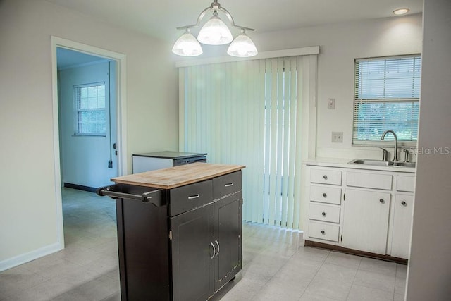 4725 Kayworth Rd, Lake Wales, FL 33898 - kitchen with a sink, white cabinets, pendant lighting, dark cabinets, and baseboards