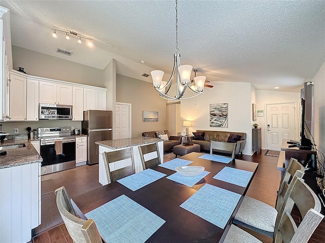 2696 Hemingway Ave, Haines City, FL 33844 - dining area featuring a textured ceiling, a chandelier, dark wood-type flooring, and lofted ceiling