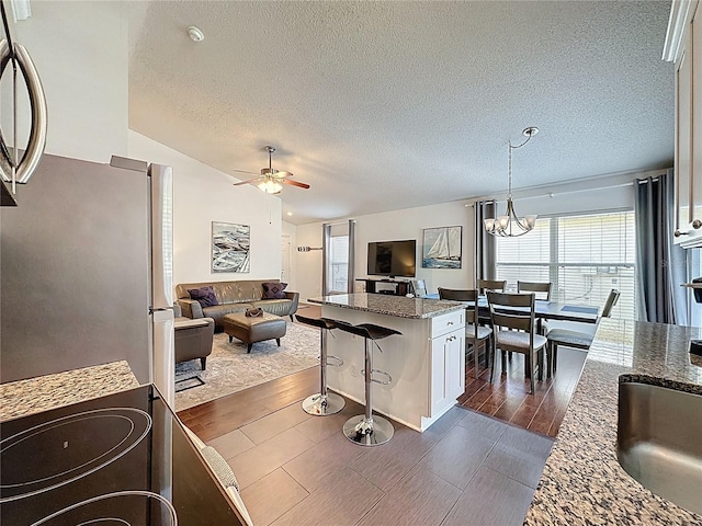2696 Hemingway Ave, Haines City, FL 33844 - kitchen featuring freestanding refrigerator, open floor plan, a ceiling fan, dark stone countertops, and a textured ceiling