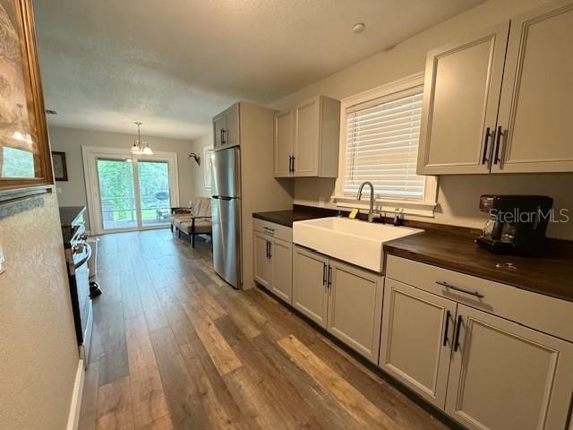 1885 Pfundstein Rd, Babson Park, FL 33827 - kitchen featuring freestanding refrigerator, wood finished floors, range with gas cooktop, and decorative light fixtures