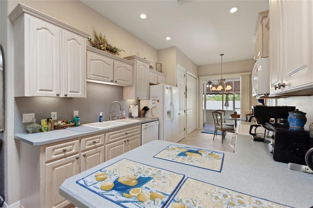 kitchen with white appliances, a notable chandelier, sink, white cabinets, and pendant lighting