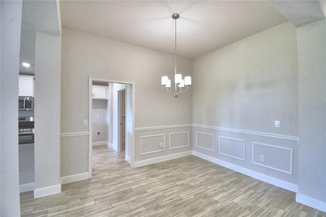 unfurnished room with light hardwood / wood-style floors and a chandelier