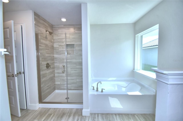 bathroom featuring wood-type flooring and shower with separate bathtub