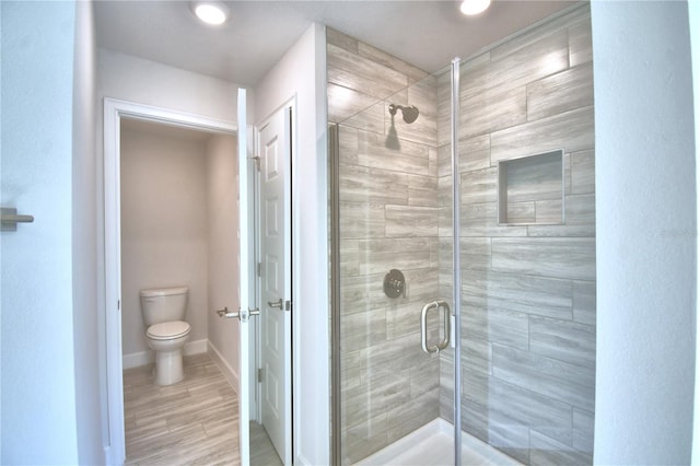 bathroom featuring toilet, hardwood / wood-style floors, and walk in shower