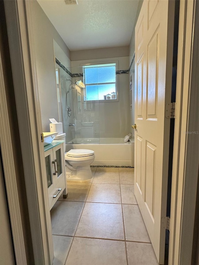 full bathroom with tiled shower / bath, toilet, tile floors, and vanity